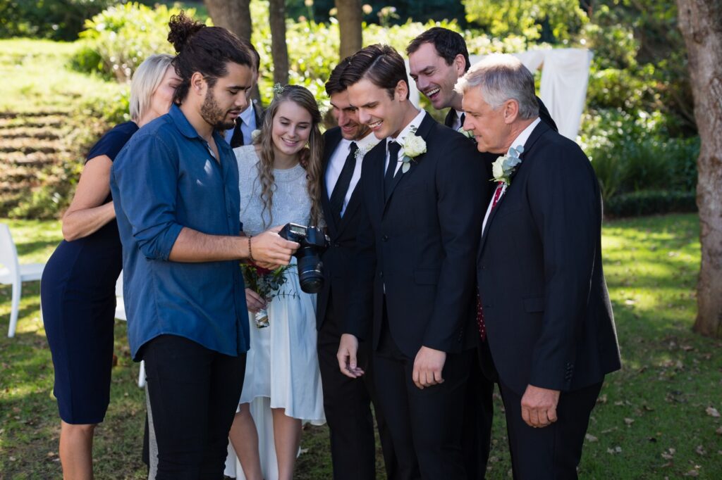 Fotógrafo enseñando las fotos en la cámara a los invitados de una boda en un jardín