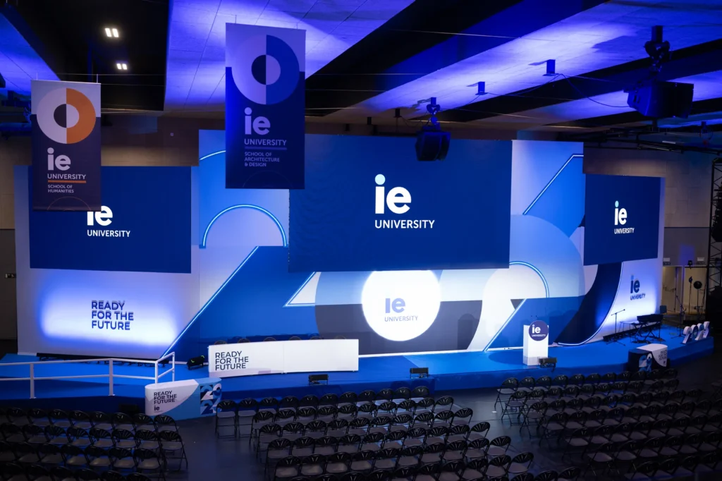 Auditorio con escenario iluminado en azul preparado para un evento corporativo