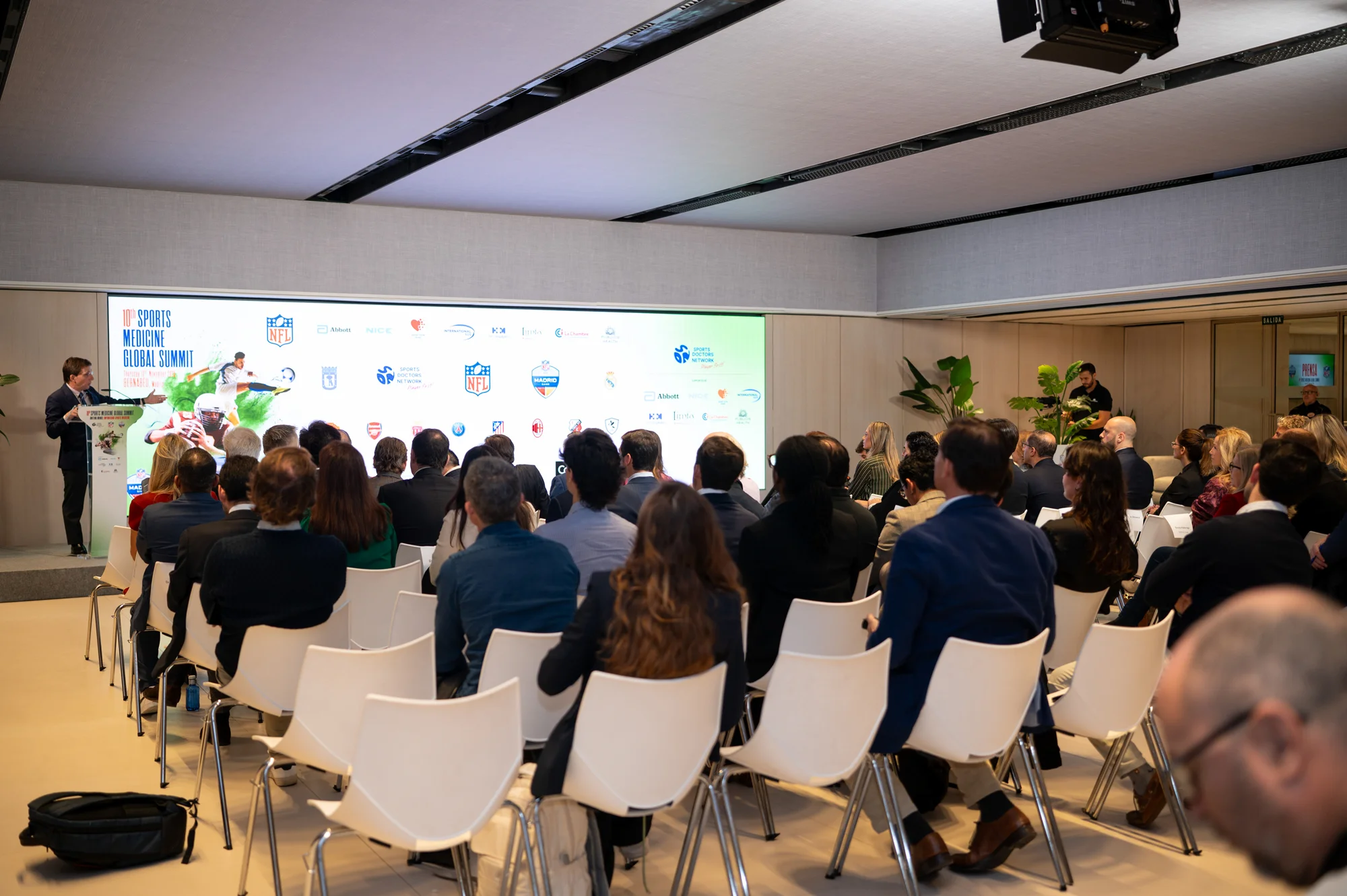 Sala llena de asistentes durante una conferencia vista desde el fondo