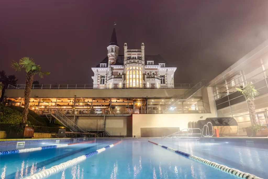 Club deportivo iluminado de noche con su piscina exterior en primer plano