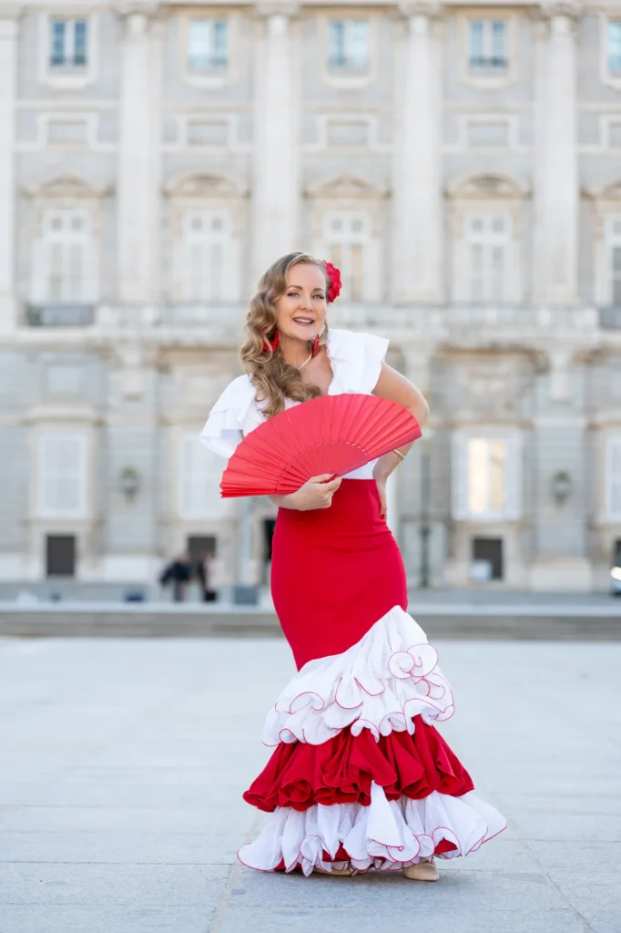 Mujer con traje de flamenca rojo y abanico posando frente al Palacio Real de Madrid