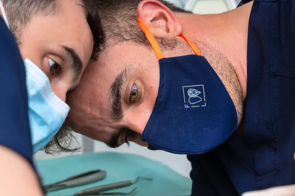 Dentista con mascarilla azul concentrado trabajando en primer plano en su clínica