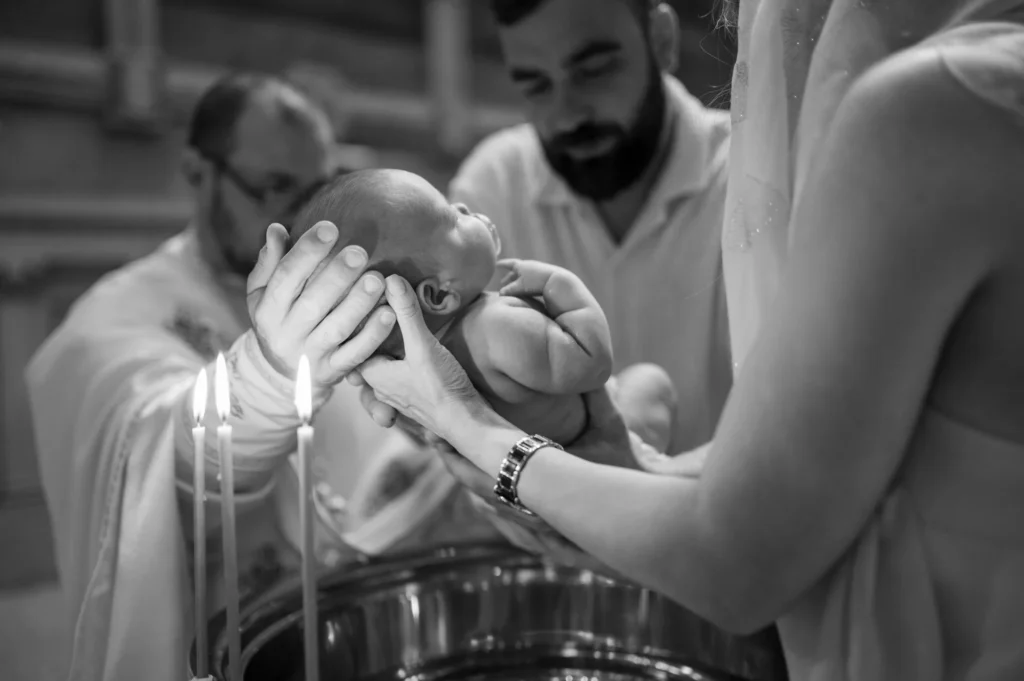 Sacerdote bautizando al bebé junto a las velas en una fotografía en blanco y negro