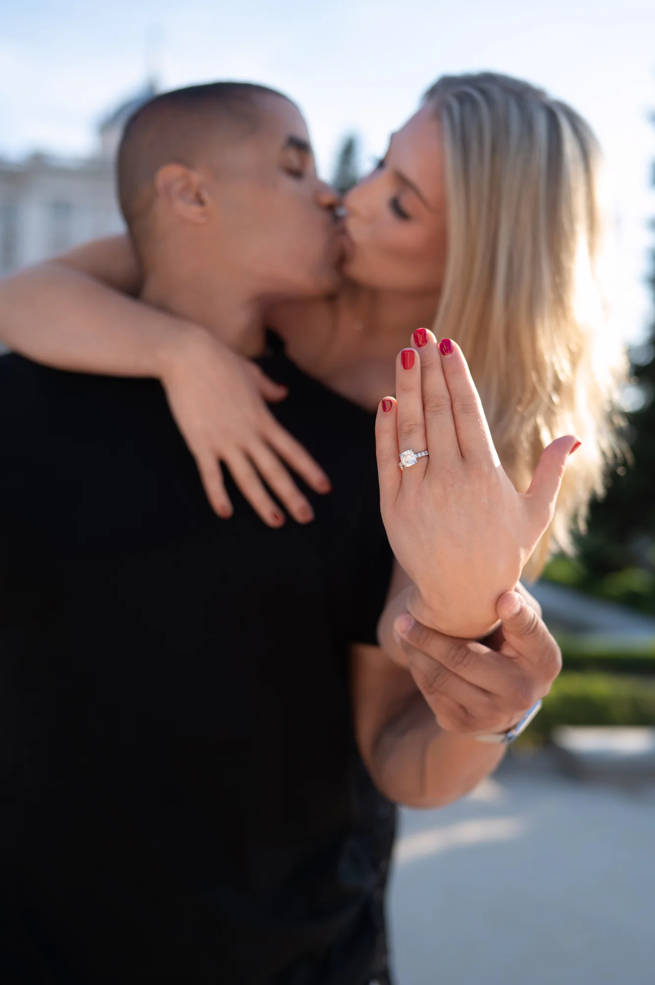 Pareja besándose y ella enseñando el anillo de compromiso en su mano
