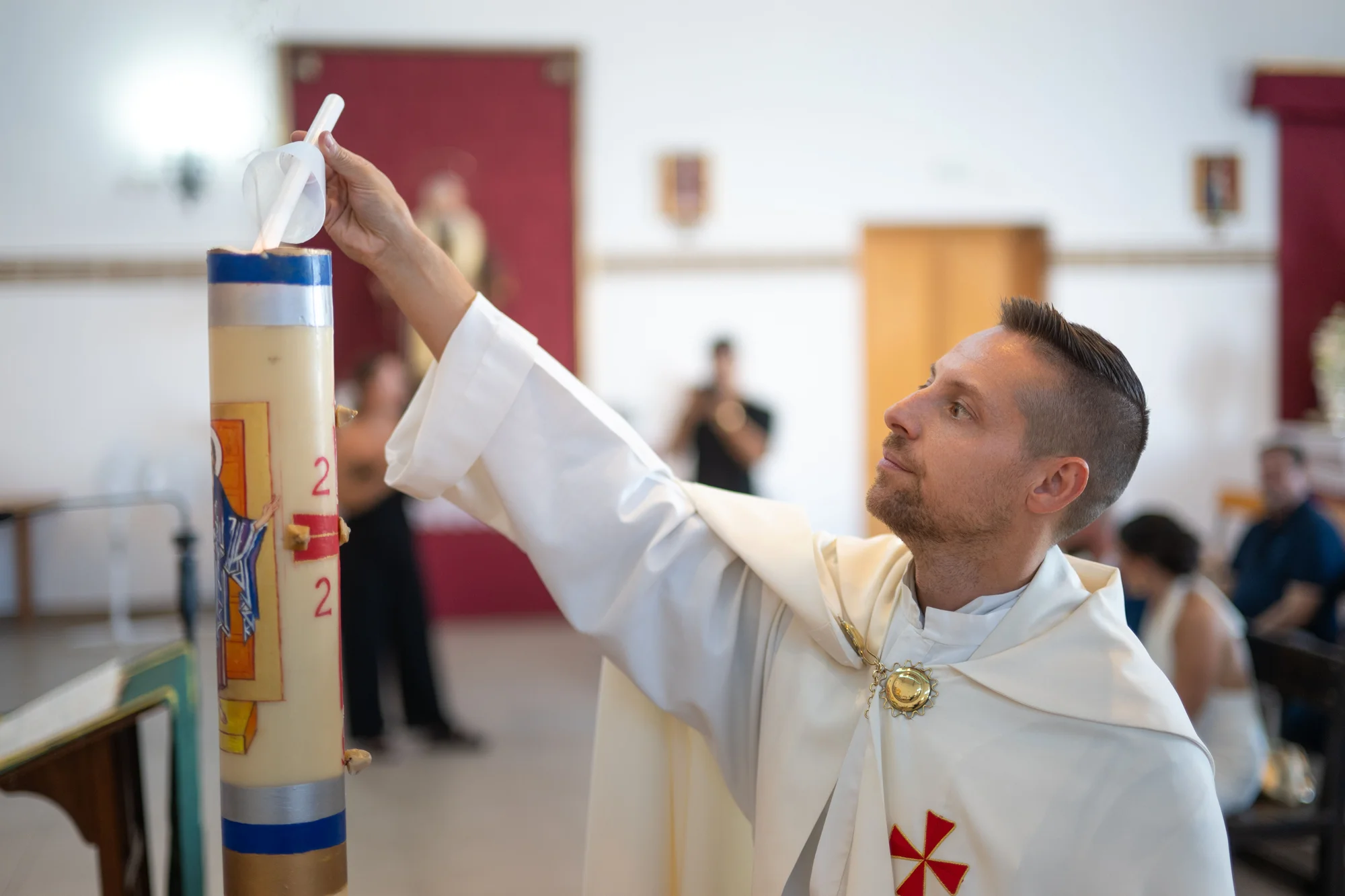 Sacerdote encendiendo el cirio pascual durante una ceremonia de bautizo