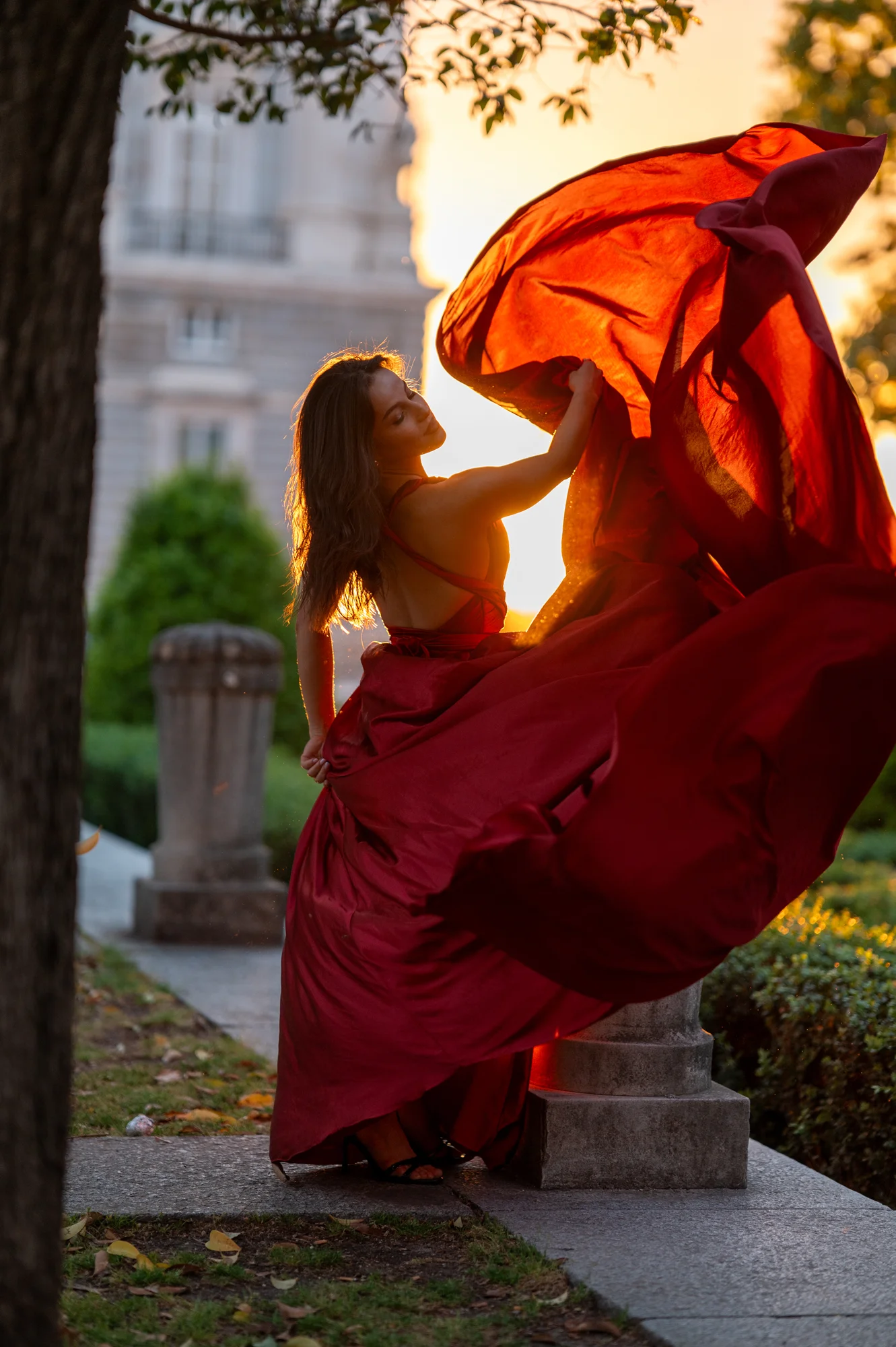 Mujer con vestido rojo al viento a contraluz del atardecer en un parque de Madrid