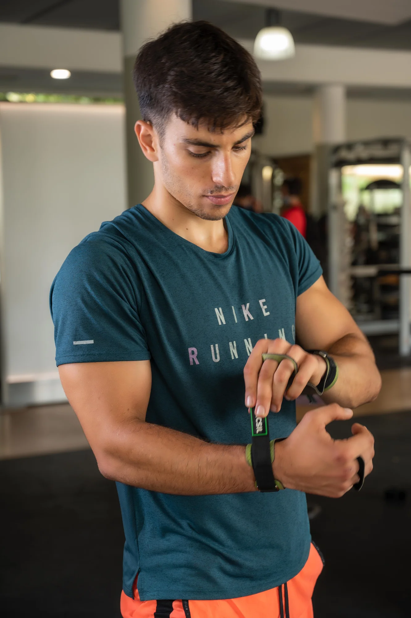 Hombre con camiseta técnica ajustándose el reloj deportivo antes de entrenar en el gimnasio