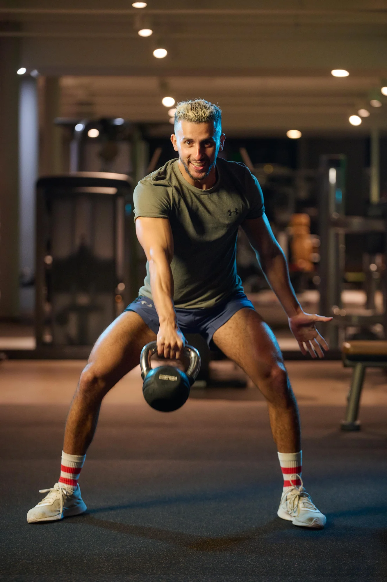 Hombre levantando una kettlebell entre las piernas en un gimnasio