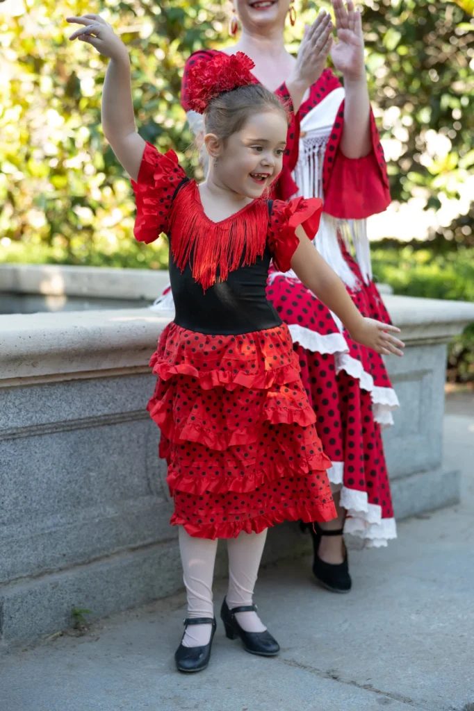 Madre e hija con trajes de flamenca rojos bailando junto a una fuente en Madrid
