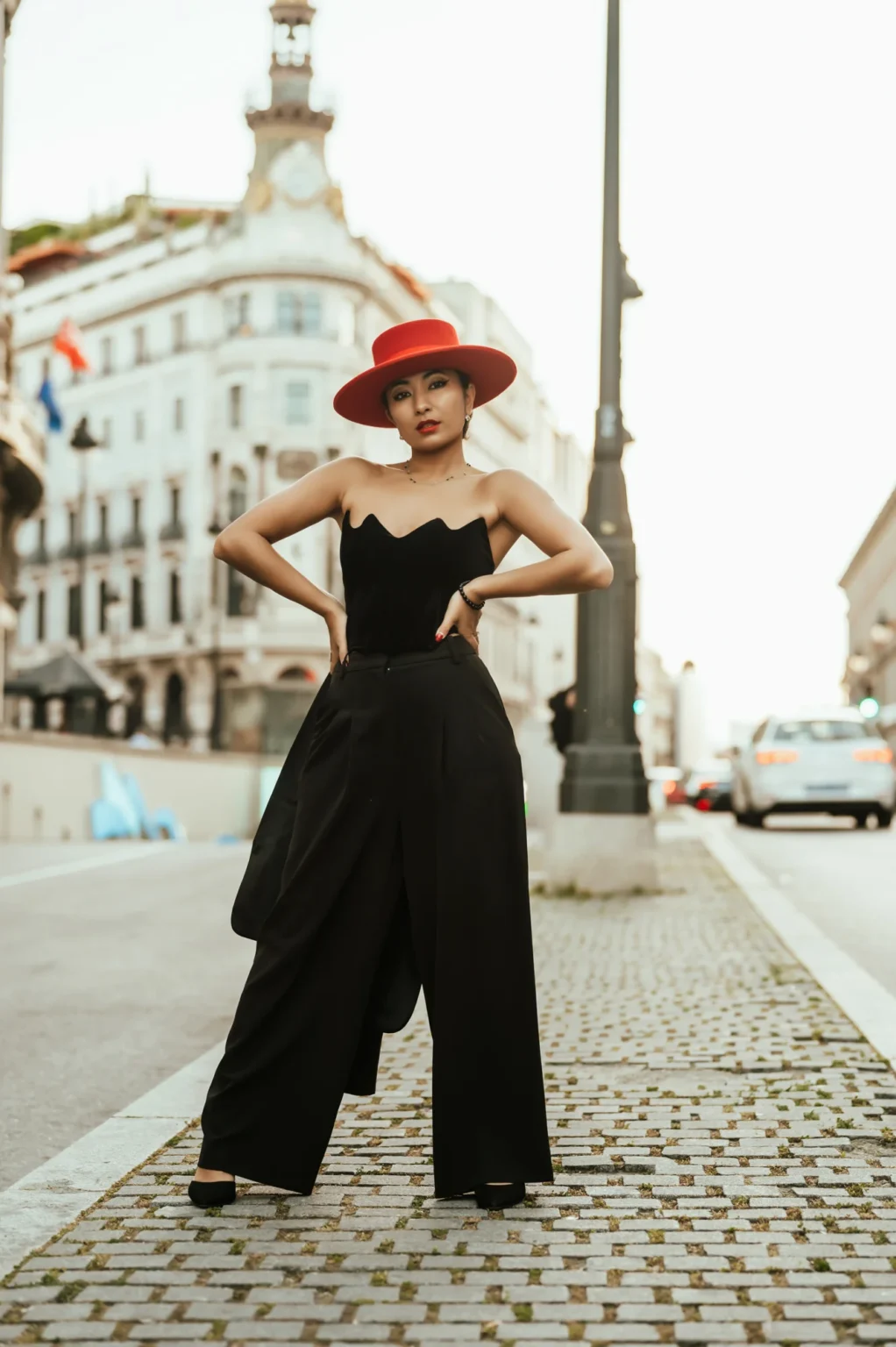 Modelo con sombrero rojo y mono negro en una calle empedrada del centro de Madrid