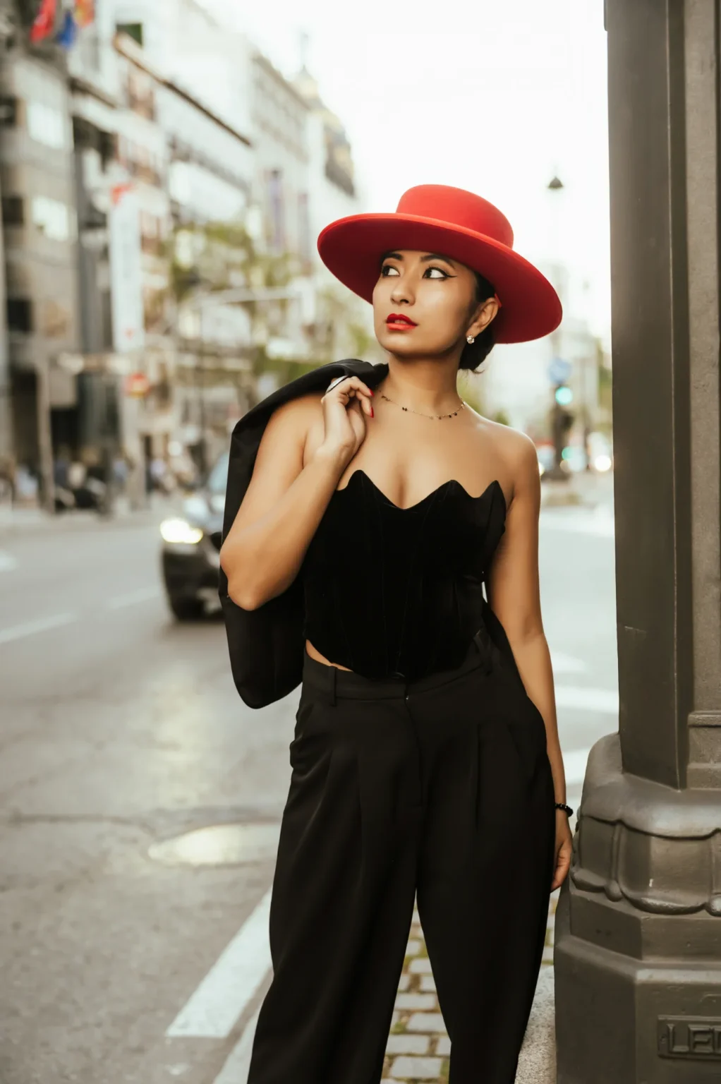 Modelo con sombrero rojo y top palabra de honor negro en una calle de Madrid