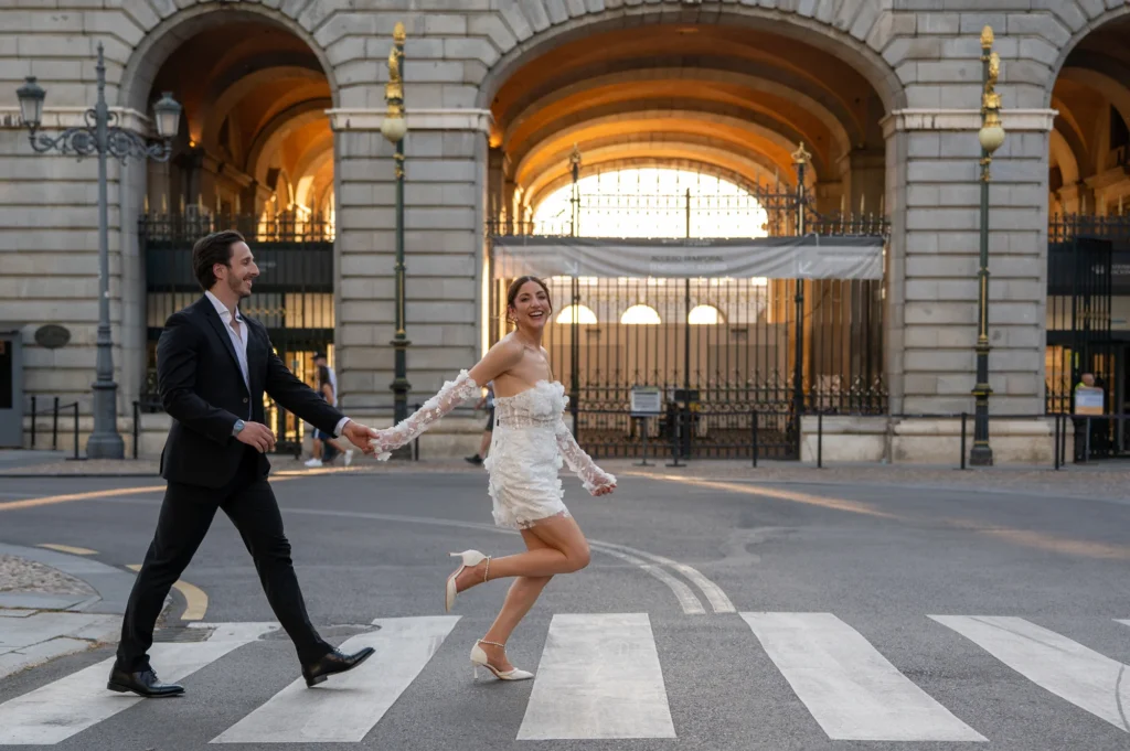 Pareja cruzando un paso de cebra bajo los arcos de piedra del centro de Madrid