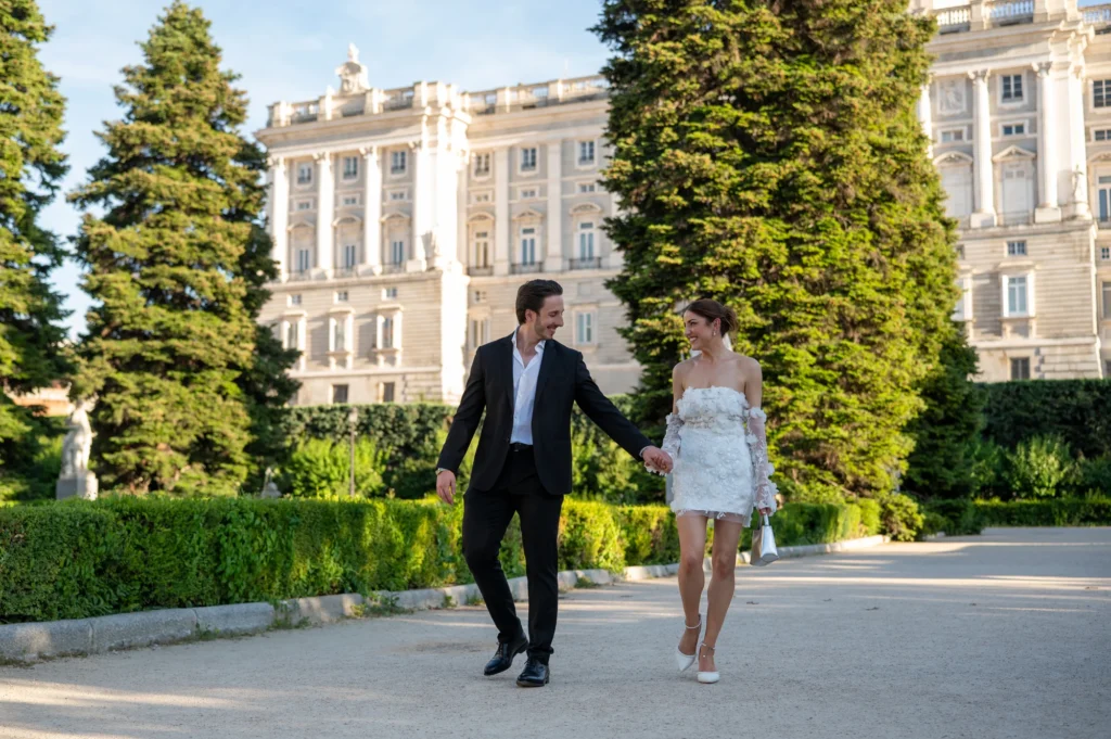 Pareja paseando de la mano por los Jardines de Sabatini frente al Palacio Real