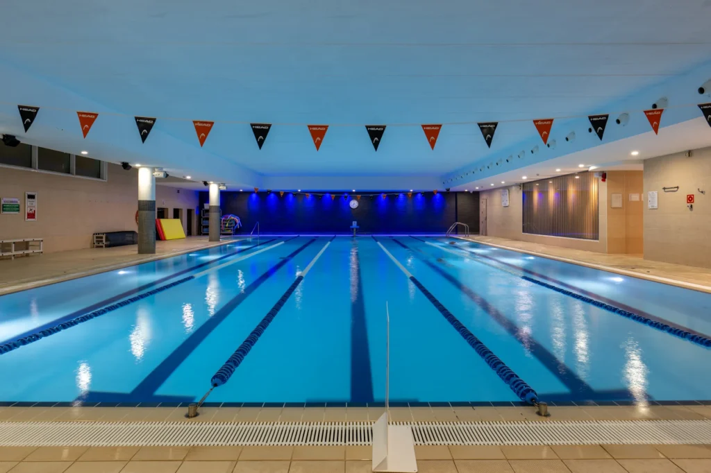 Piscina cubierta de competición con calles y banderines en un club deportivo