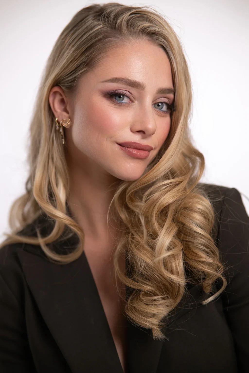 Primer plano de una modelo rubia con blazer negro mirando a cámara