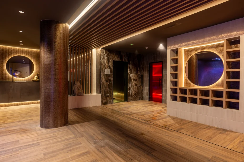Recepción del spa con columna de piedra, espejo circular y luz cálida