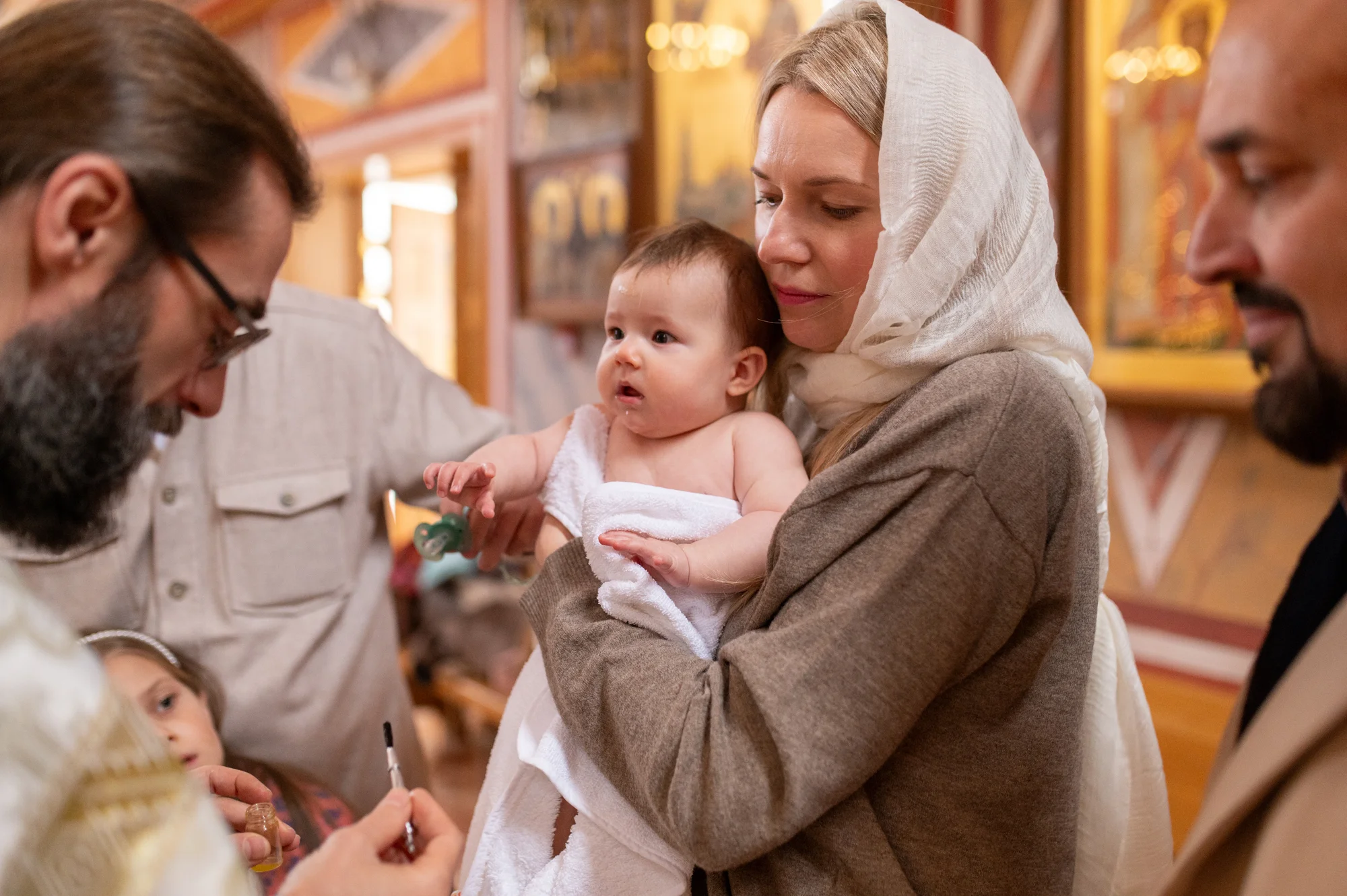 Padres con su bebé en brazos durante la ceremonia de bautizo en una iglesia ortodoxa