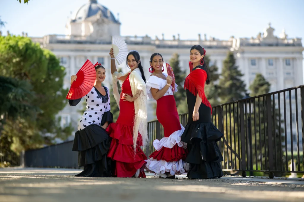 Cuatro mujeres con trajes de flamenca posando frente al Palacio Real de Madrid
