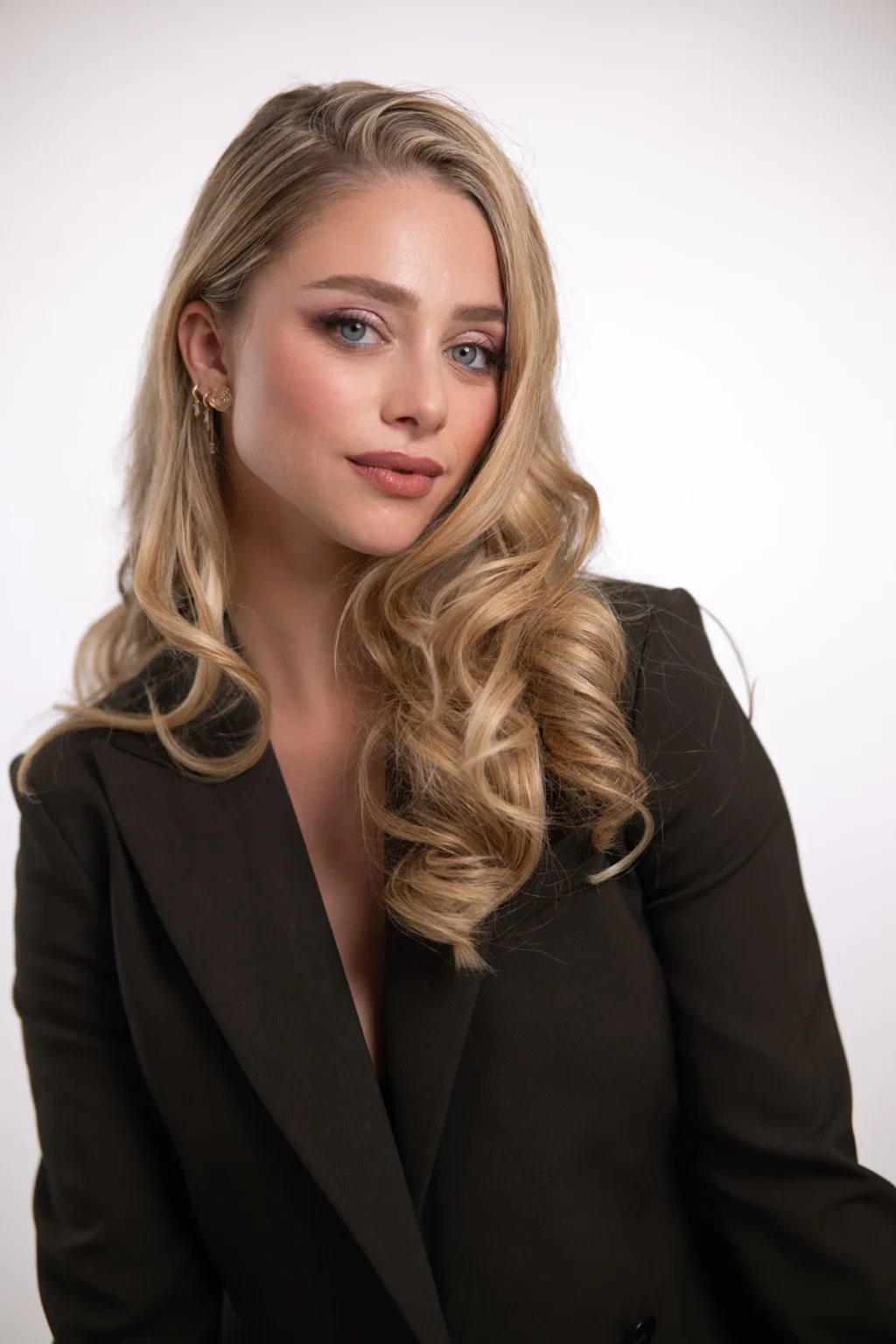 Retrato de estudio de una modelo rubia con chaqueta oscura y pelo ondulado