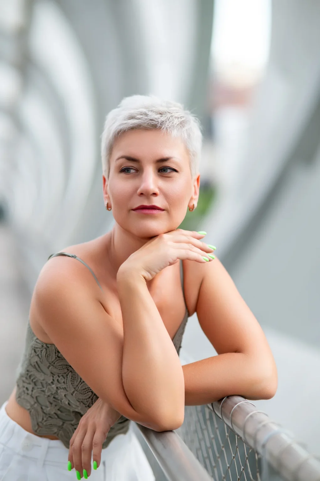 Retrato de una modelo de pelo corto platino apoyada en una barandilla metálica