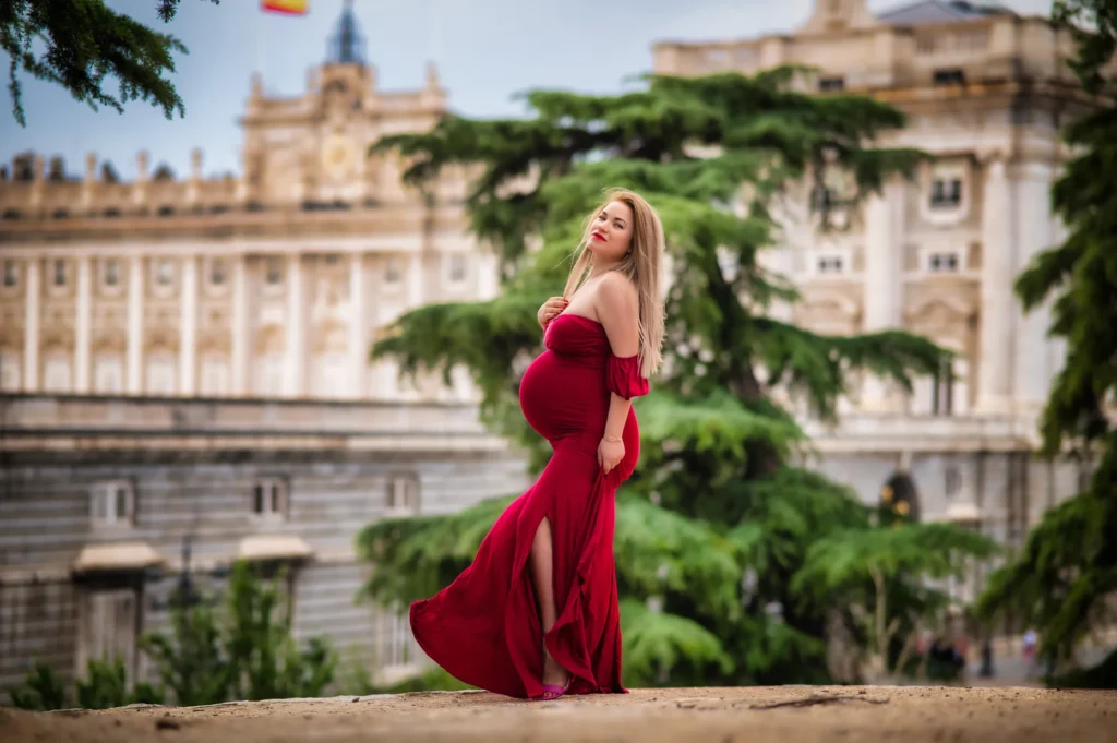 Embarazada con vestido rojo ceñido posando frente al Palacio Real de Madrid