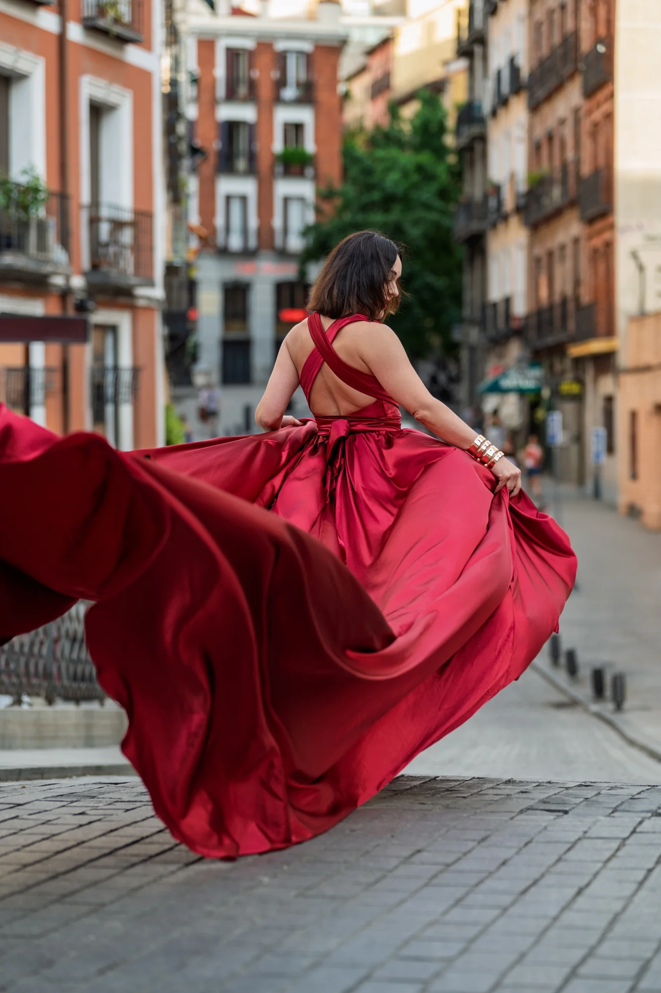 Mujer de espaldas con vestido rojo girando en una calle del barrio de Las Letras