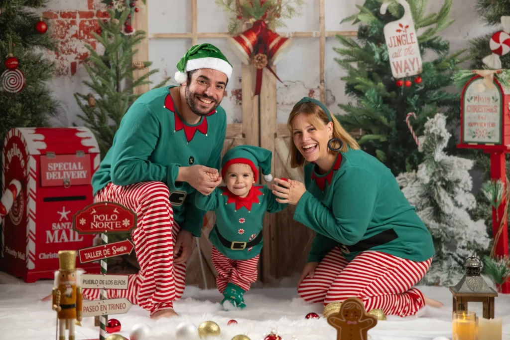 Familia vestida de elfos con pijamas de rayas en el decorado del taller de Papá Noel