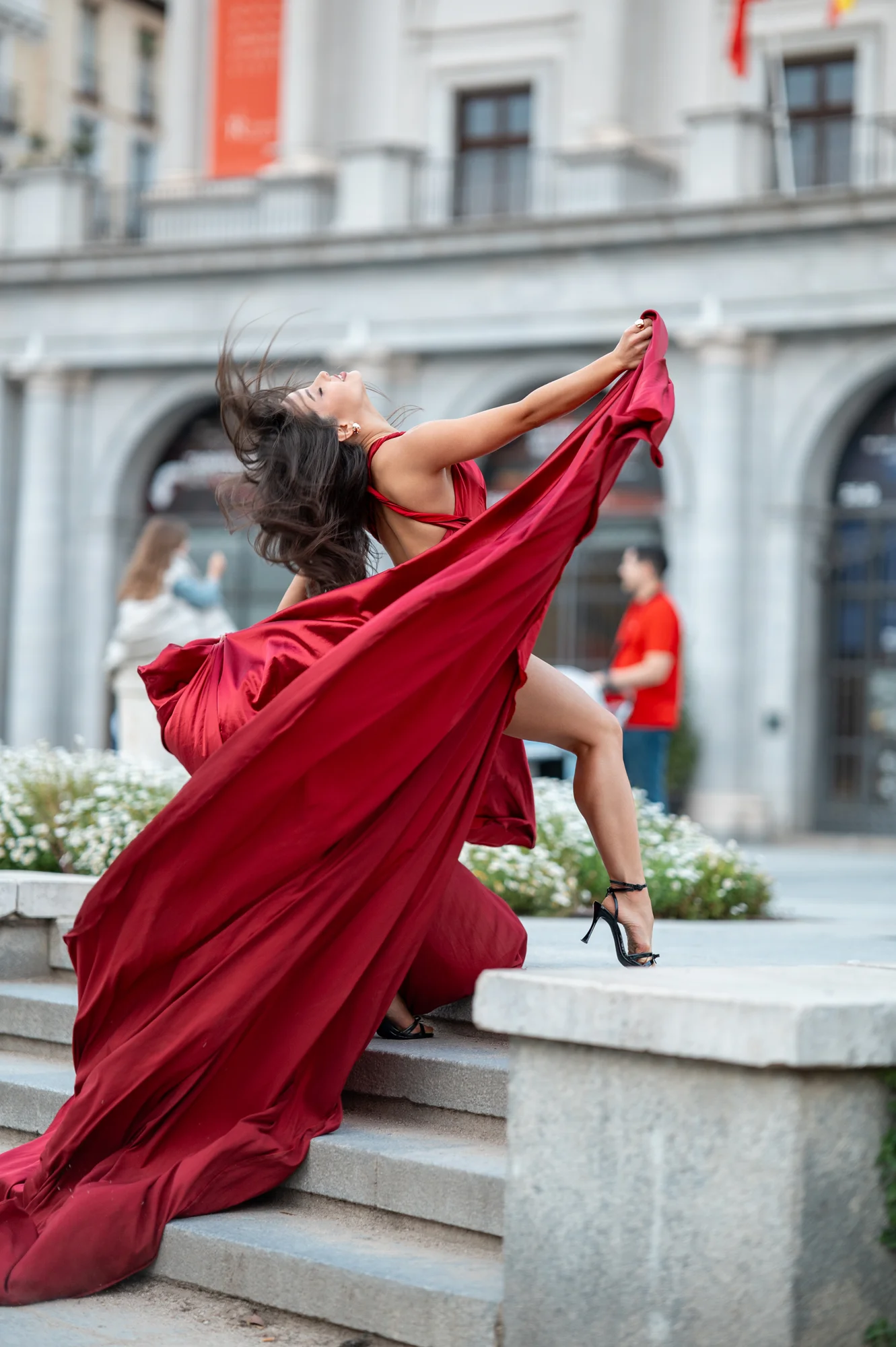 Mujer con vestido rojo al viento en una escalinata del centro de Madrid