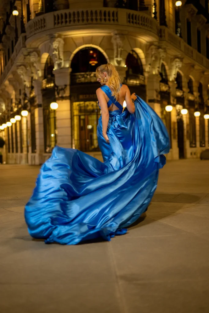 Mujer de espaldas con vestido azul al vuelo bajo los soportales iluminados de noche en Madrid