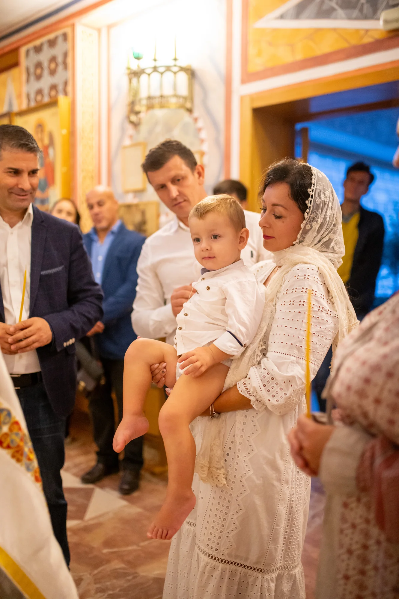 Familia e invitados rodeando al bebé en brazos de su madre durante el bautizo