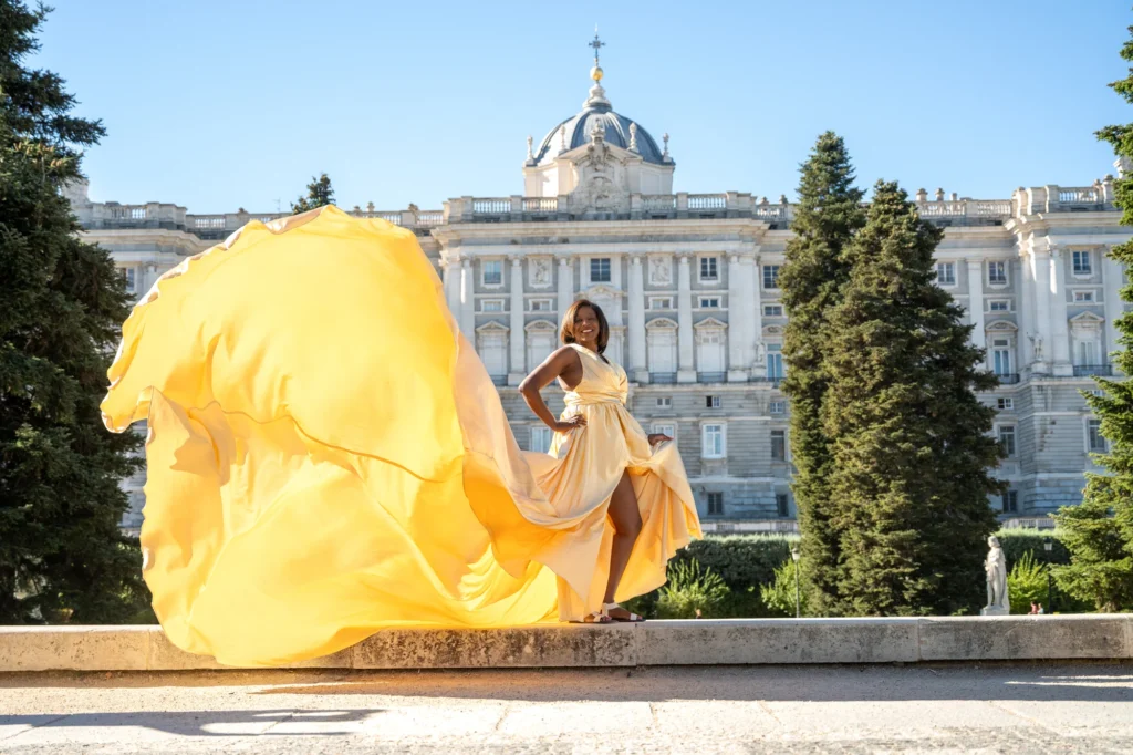 Mujer con vestido de vuelo amarillo frente al Palacio Real de Madrid