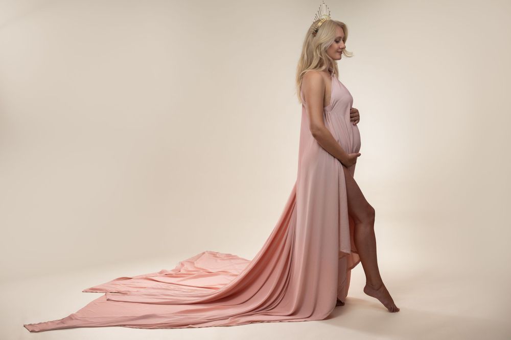 Embarazada envuelta en una tela rosa en el estudio