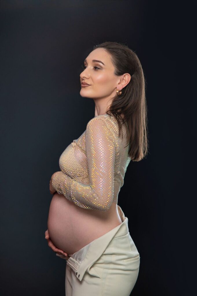 Embarazada con top brillante y pantalón blanco