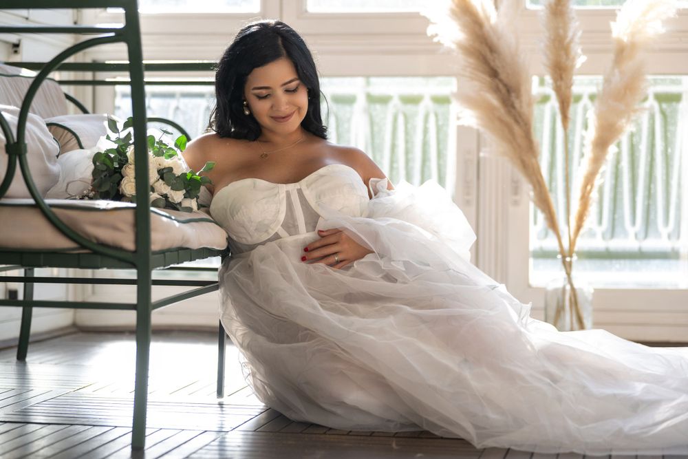 Embarazada con vestido blanco voluminoso sentada en la terraza